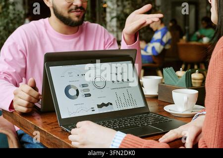 Business Partners Analyzing Market Data on Laptop in Cafe Stock Photo