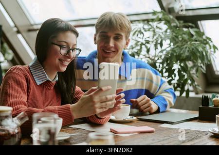 Woman and Man Looking at Smartphone Screen in Cafe Stock Photo