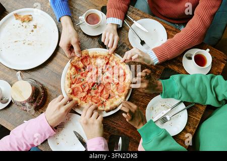 Diverse Group of Friends Sharing Pizza Slices in Cafe Stock Photo