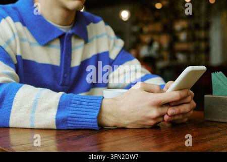 Man Using Smartphone for Messaging in Cafe Stock Photo