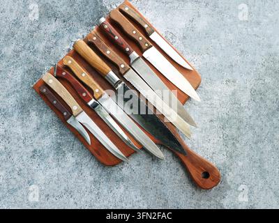 Collection of Various Kitchen Knives on Textured Surface Stock Photo