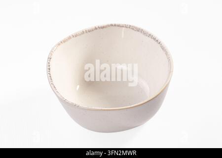 Empty ceramic bowl with subtle grey speckles and rough dark rim edge, set against pure white background. Tableware product shot Stock Photo
