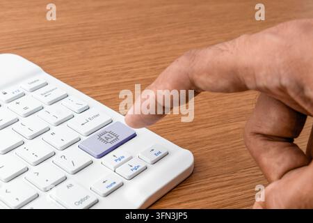Human hand pressing a dedicated AI button on a white computer keyboard. Artificial intelligence integration, future technology, automation Stock Photo