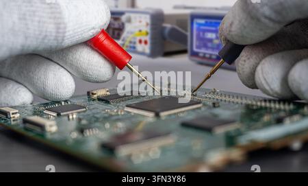 Technicians perform quality control on a circuit board in a manufacturing facility to test and ensure technology upgrade and replacement. Stock Photo
