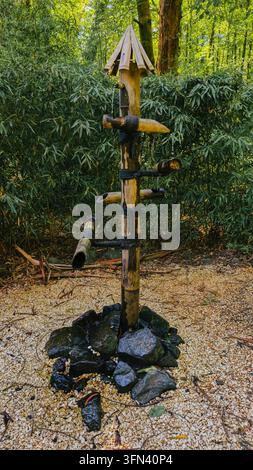 A traditional shishi-odoshi bamboo fountain stands in a lush Japanese-style garden during daylight, adding water, movement and Zen atmosphere to the l Stock Photo