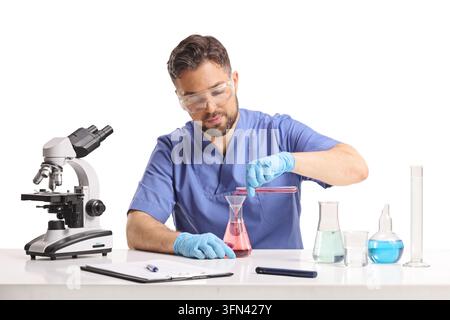 Young male scientist pouring liquid from a test tube into a flask isolated on white background Stock Photo