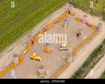 Aerial view of a pumpkin-themed display featuring hay bale structures, a toy train, and a toy truck arranged in a field in Gdansk, Poland. Stock Photo