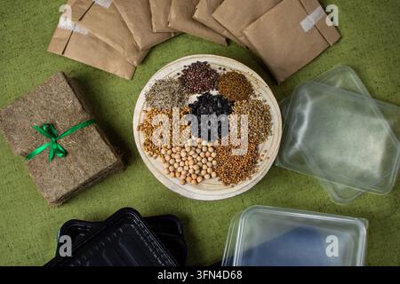 Microgreens growing kit with seeds scattered on a wooden stand. Complete home microgreens growing kit is displayed as flat lay on textured green fabri Stock Photo