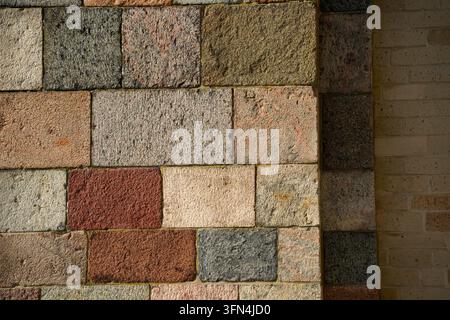 Close-up of a rustic masonry wall built from multicolored granite and sandstone blocks in varied earth tones, Ribe, Denmark. Stock Photo