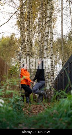 Happy man and woman in warm casual clothing enjoying romantic moment together among autumn birch trees Stock Photo