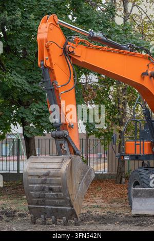 Close-up of an orange excavator arm with exposed hydraulic cylinders ...