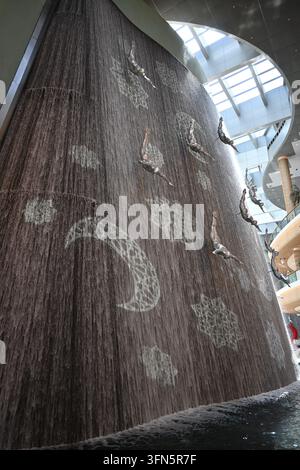 A high-angle view of a large installation featuring numerous dolphin sculptures suspended from the ceiling. The sculptures are arranged in a pattern a Stock Photo
