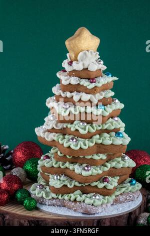 Decorative Christmas tree made from star-shaped festive cookies and decorated with festive Christmas ornaments and pine cones. Creative edible decorat Stock Photo
