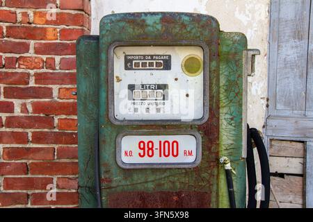 A close-up shot shows the mechanical dial of a vintage green and rusty petrol pump dispenser. The metallic surface features cracked paint, while a red Stock Photo
