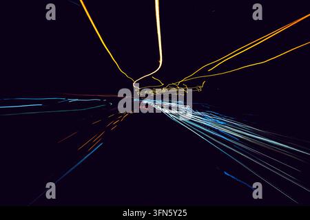 Vibrant light trails in various colors create an abstract composition against a dark backdrop. The blurred lines suggest movement and speed, evoking a Stock Photo