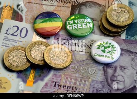 Green Party political badges with sterling banknotes and coins, illustrating party funding in UK politics. Stock Photo