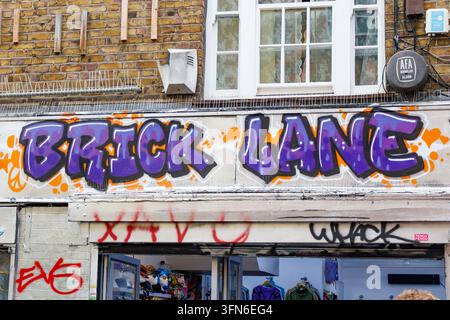 Purple spray painted graffiti sign reading Brick Lane above shop front in London United Kingdom Stock Photo