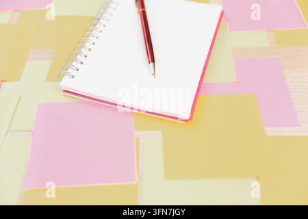 Open spiral notebook with a pen resting on colorful sticky notes across a wooden desk, representing planning, organization, brainstorming, productivit Stock Photo
