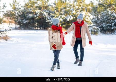 Smiling Young Couple, Male And Female, Enjoying A Winter Walk Together In A Snowy Outdoor Setting, Wearing Warm Clothes, Creating A Joyful Atmosphere Stock Photo