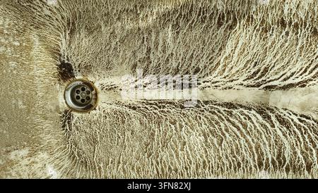 Dirty white bathtub covered with heavy brown mud and rust Stock Photo
