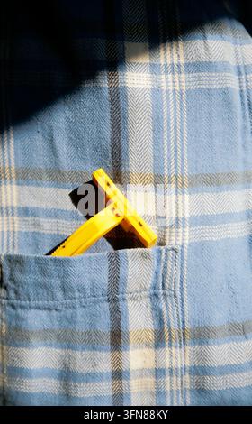 Close up of yellow disposable razor blade on plaid shirt pocket Stock Photo