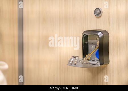Open key lock box mounted on a wooden wall with apartment keys inside ready for guest pickup. Concept of contactless key handover and safe self check- Stock Photo