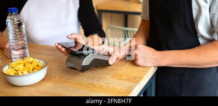 Banner of anonymous customer making contactless payment using smartphone in cafe Stock Photo