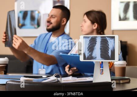 Medical diagnosis and healthcare collaboration, doctors reviewing chest x-ray on tablet and film in hospital office with professional team consultatio Stock Photo
