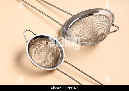 Food preparation and culinary tools, two stainless steel kitchen strainers for cooking and baking on a neutral background Stock Photo