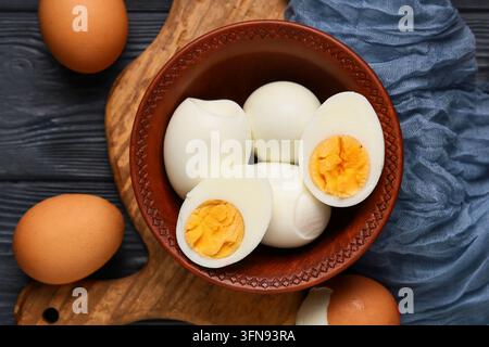 Healthy nutrition and protein diet, hard boiled eggs in a rustic ceramic bowl on a wooden cutting board with raw eggs for breakfast food preparation Stock Photo