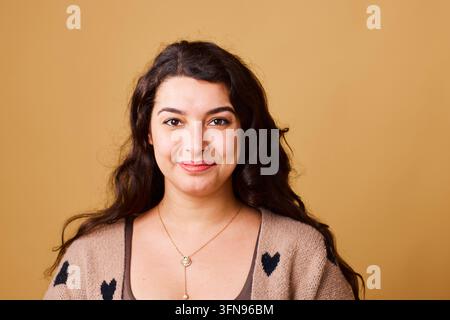 Confident Young Woman Smiling Portrait Wearing Heart Sweater And Necklace On Beige Background Stock Photo