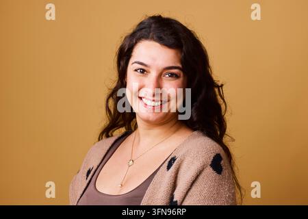 Smiling Woman Portrait Looking Confident and Friendly in Warm Studio Lighting Stock Photo