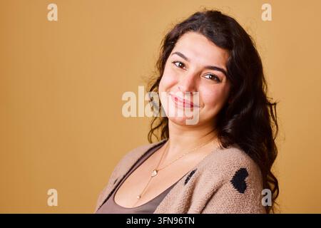 Smiling Young Woman Portrait in Cozy Sweater Warm Studio Headshot Conveying Confidence and Friendliness Stock Photo