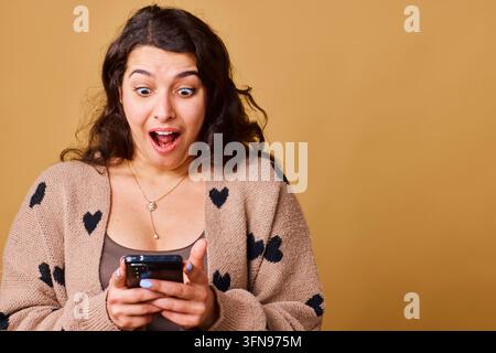 Surprised Young Woman Looking At Smartphone With Excited Reaction While Reading Message Stock Photo