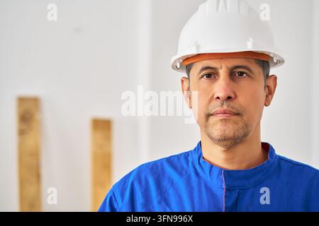 Portrait, or construction engineer in renovation site with helmet. Confident, hispanic man or contractor in building, property development or infrastr Stock Photo