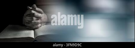 Hands of praying young man and Bible on a wooden desk background Stock Photo