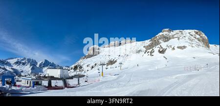 Panoramic view of alpine ski resort above Corvara in Alta Badia, featuring groomed slopes, mountain lifts, dramatic rocky peaks and huge copy space un Stock Photo