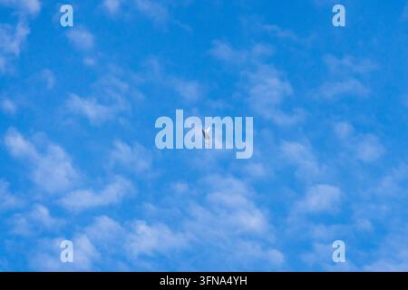 View of a fighter jet flying through a bright blue sky with scattered white clouds over Mosnov, Moravian-Silesian Region, Czechia. Stock Photo