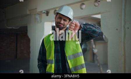Displeased Caucasian architect man showing thumbs down construction site unhappy foreman rejecting result male guy builder expressing disapproval Stock Photo