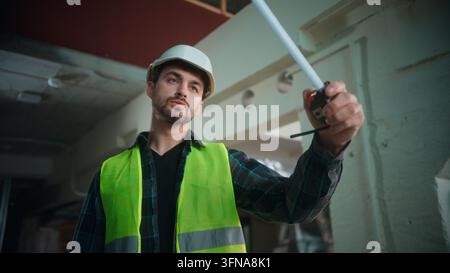 Professional Caucasian builder man measuring construction parts with tape male engineer uniform checking dimensions use tool foreman planning repair Stock Photo