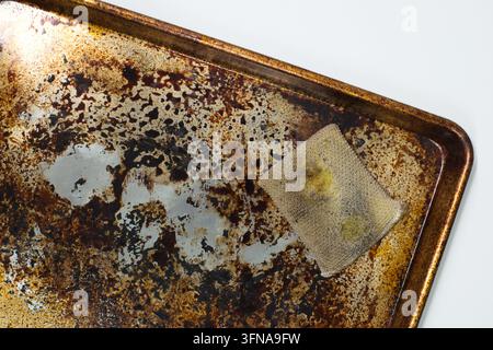 Dirty stained cookie sheet aluminum baking pan bakeware with old cleaning sponge. Stock Photo