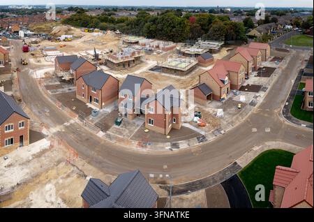 Aerial landscape view above a construction site building new and affordable eco friendly houses to fill the social housing shortage in the UK on green Stock Photo
