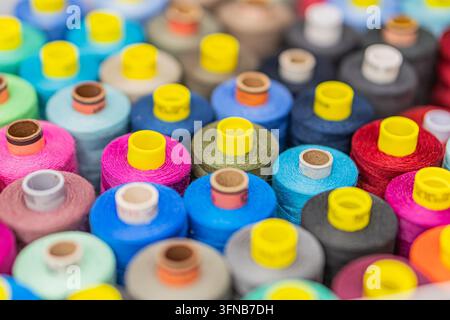 A scatter of multi-colored thread spools on a neutral background, arranged in an aesthetically pleasing yet random pattern Colors range from reds, blu Stock Photo