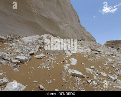 Chalk cliff and rockfall beneath a blue sky, photographed at White Desert National Park in Egypt's Western Desert. Stock Photo