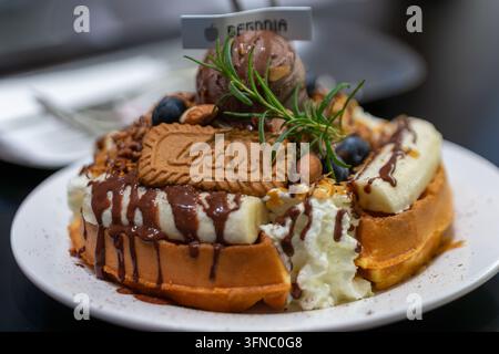 Delicious waffle topped with chocolate, banana, whipped cream, and ice cream Stock Photo