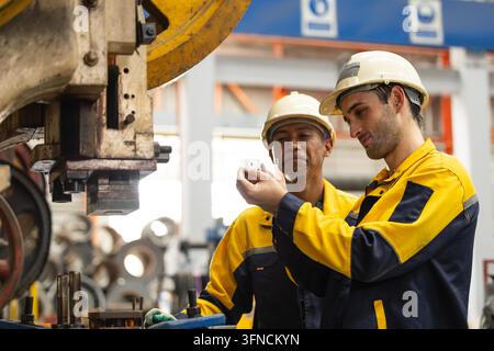 Industrial Technician Working with Stamping Machine in Factory. Stock Photo