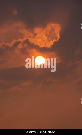 Glowing Sunset Sun Behind Dramatic Orange Cloud Formation Stock Photo