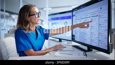Healthcare Manager Carefully Reviews Medical Claims On Computer Screen Daily. Stock Photo
