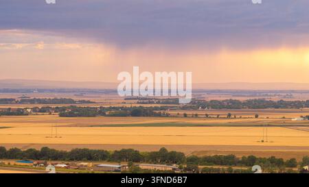 Aerial view of agricultural farmland under dramatic dark storm clouds. Rural landscape with village, green and golden fields Stock Photo