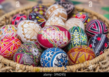 Many bright and colorful easter eggs in a wicker basket, close up. They are hand-painted or dyed Stock Photo